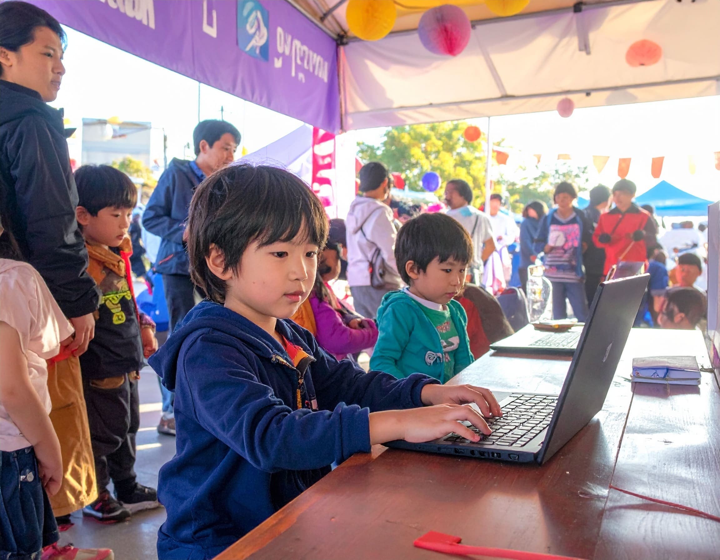 イベントブースでノートパソコンを操作し、マインクラフトを楽しむ子どもたち